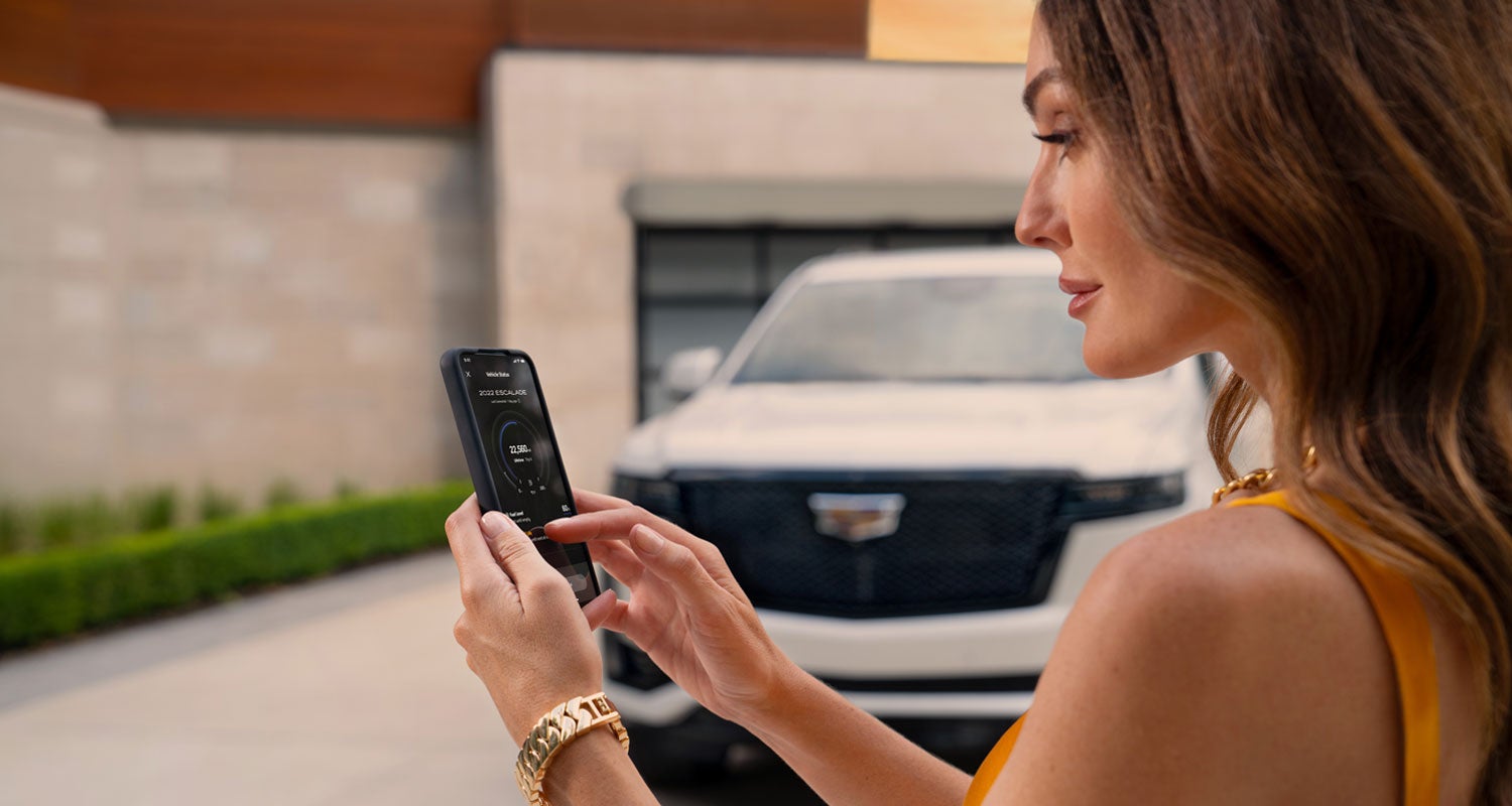 lady checking her mobile with a Cadillac vehicle background | Dan Vaden Cadillac Brunswick in Brunswick GA