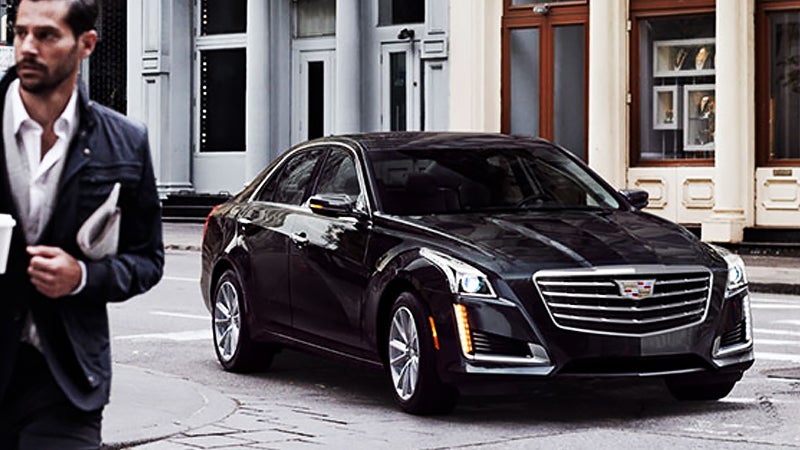 Photo of a person walking near a Cadillac CTS vehicle